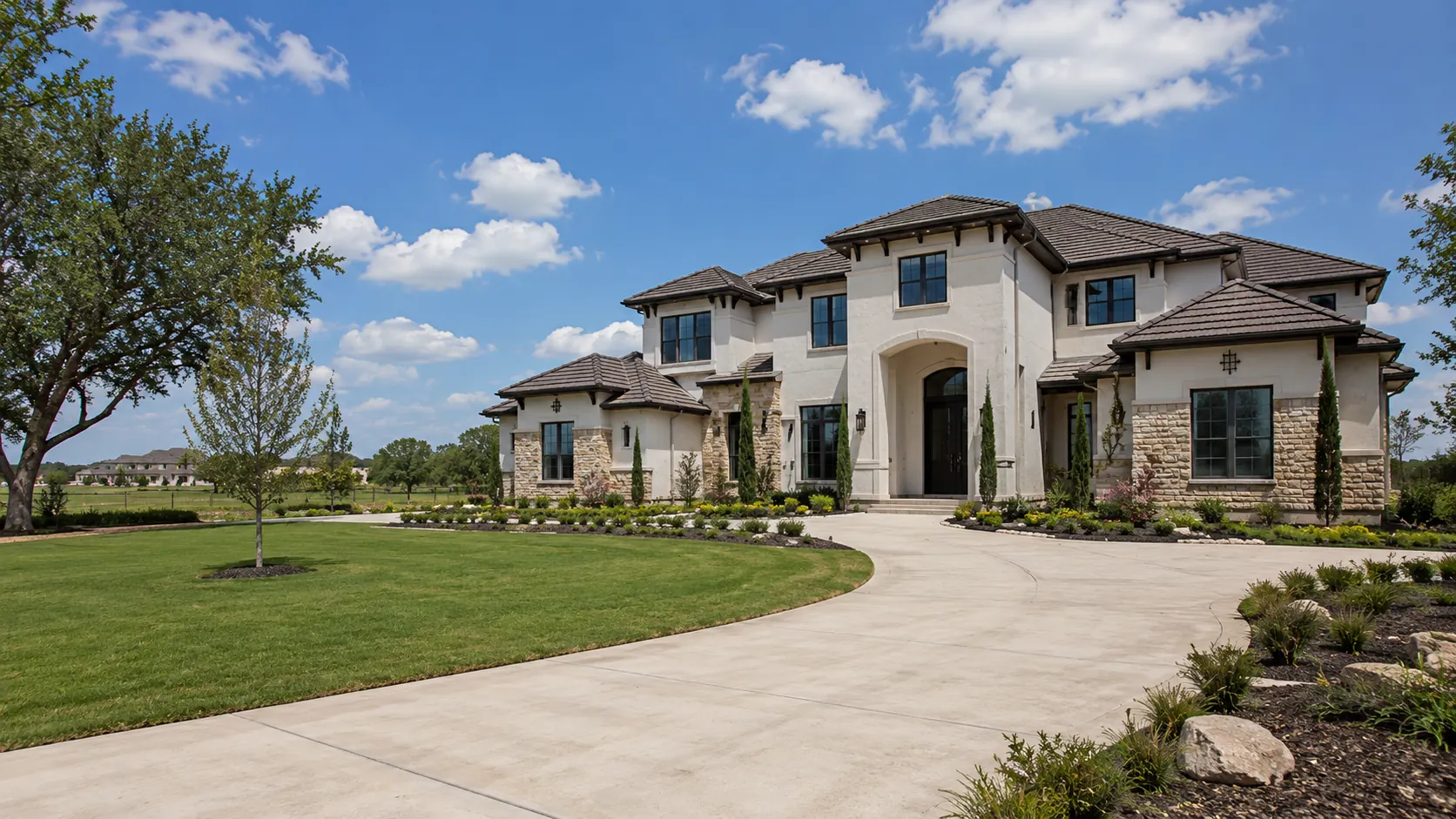 A stucco and stone Mediterranean-style custom home with a tile roof, arched entry and sweeping circular drive on open acreage near Rosenberg, Texas