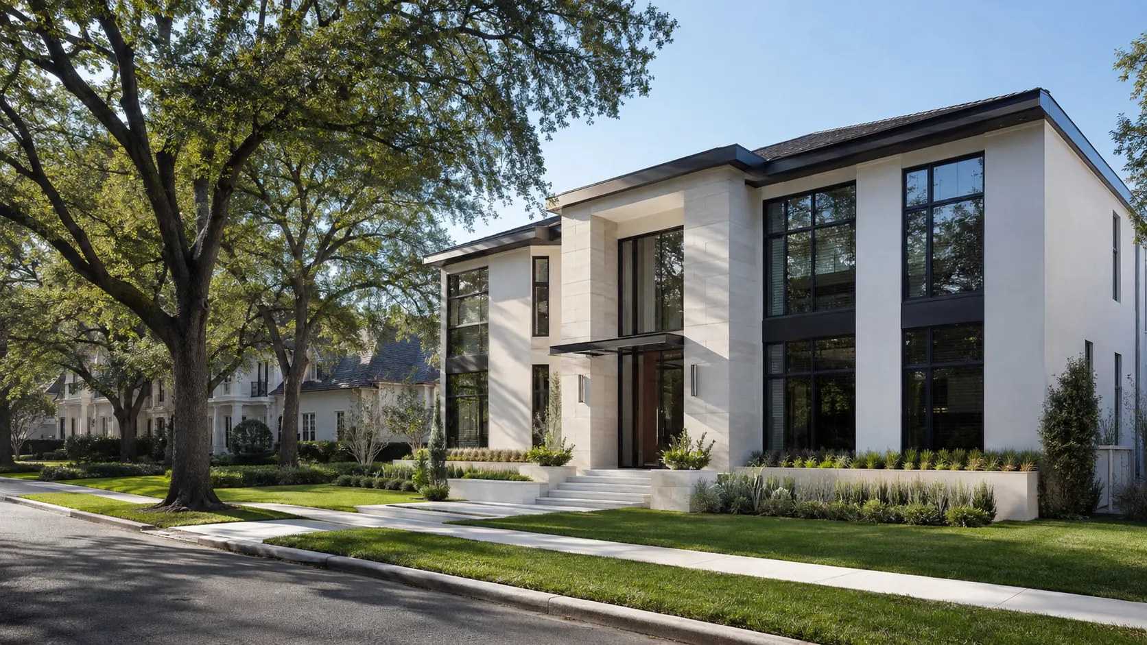 A two-story modern custom home in limestone and stucco with floor-to-ceiling black-framed glass, set close to the sidewalk under mature oaks in West University Place